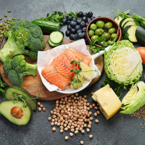 an array of healthy Mediterranean Diet foods include berries, nuts, cucumbers, avocado, olives, salmon, broccoli