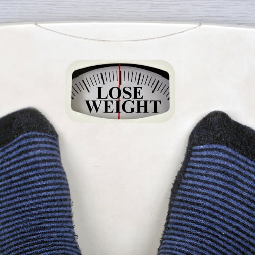person standing on a scale in their socks where the letters read lose weight