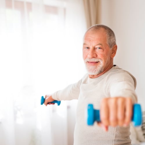 adult male exercising at home with dumbbells 