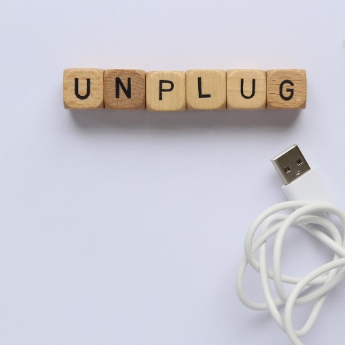 scrabble letters spelling out the word unplugged with a usb computer cable