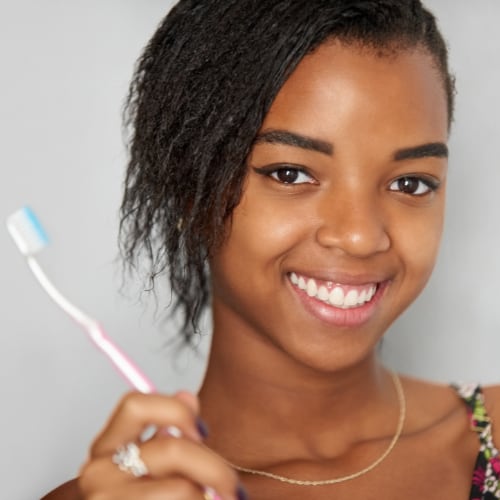 young woman smiling with her toothbrush