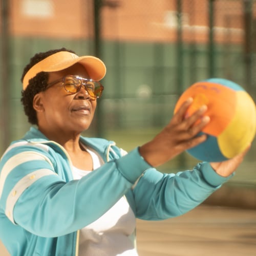 active elderly woman of color getting exercise playing with a soccer ball