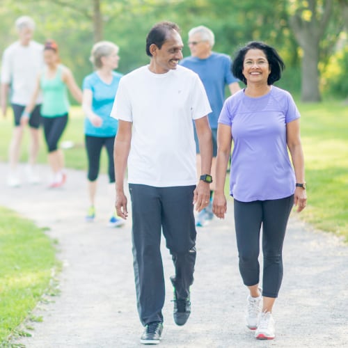 a group of adults walking togther for movement and exercise in a natural outdoor park setting 