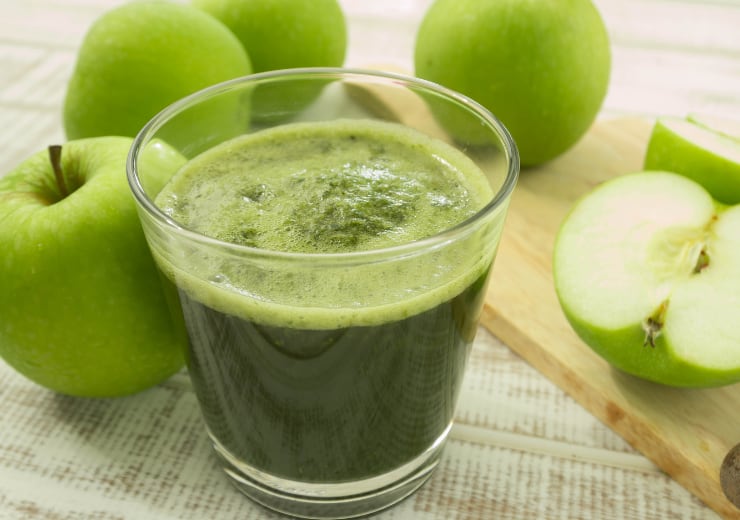 green apple juice on wooden cutting board with cut apples