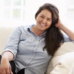 attractive, overweight hispanic woman smiling on couch