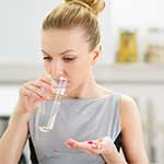 young, healthy, blonde woman drinking water taking supplements