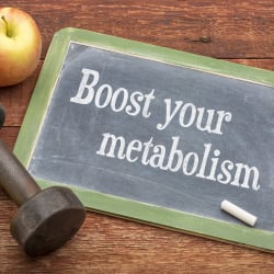 chalkboard writing says boost your metabolism accompanies by fruit, dumbbell and measuring tape