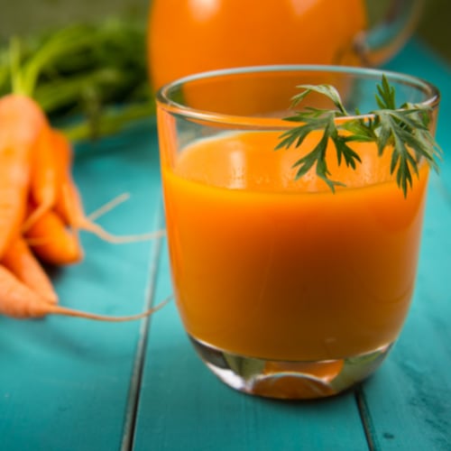 natural carrot juice in glass on blue rustic table