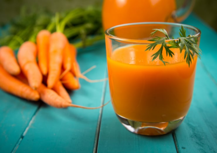 natural carrot juice in glass on blue rustic table