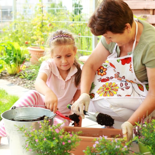 child and her grandmother gardening at home