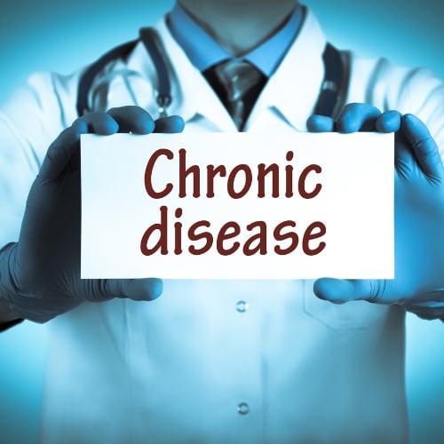 a doctor in a lab coat holding up a sign that says Chronic disease