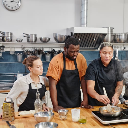 group of adults cooking togrther in a group workshop setting