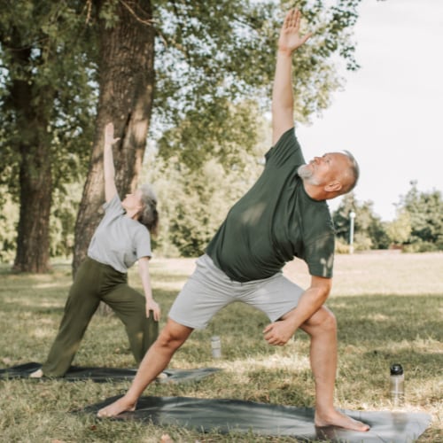 senior couple stretching together outdoors in a park area