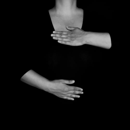 a woman with hands above and below her diaphragm demonstrating deep breathing