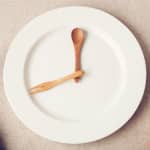 dinner plate with wooden utensils depicting time to illustrate intermittent fasting