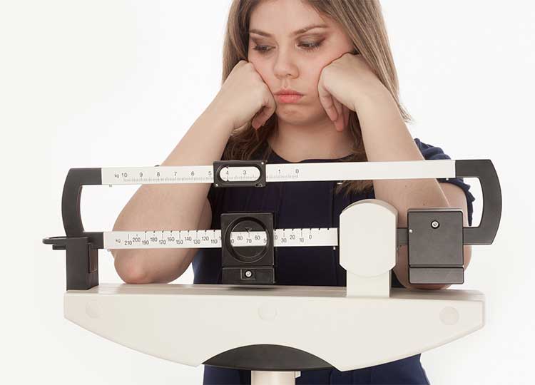 Disappointed young woman standing on medical scale