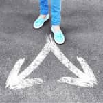 Female Feet Standing on Road with White Arrows