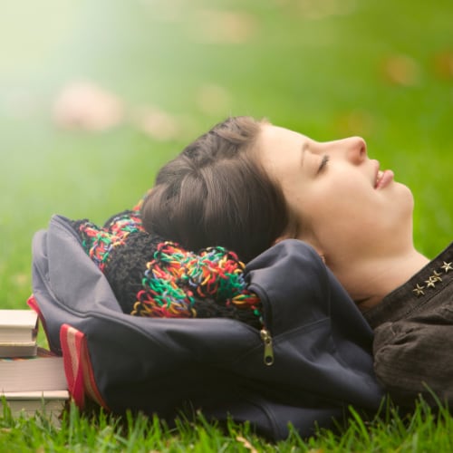 female university student resting head on backpack