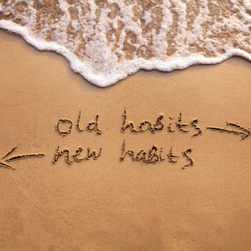 illustration of old habits to new habits drawn in the sand on the beach