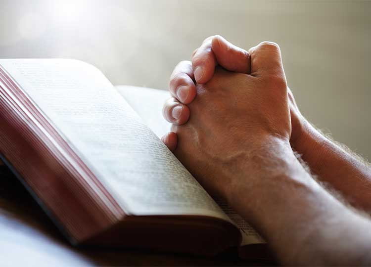 Hands Praying over Bible