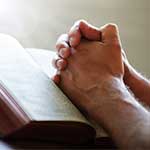 Hands Praying over Bible