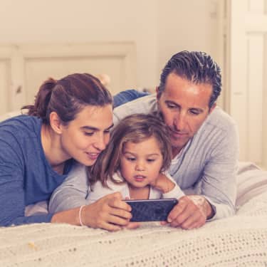 parents watching video together with their young daughter on a smartphone