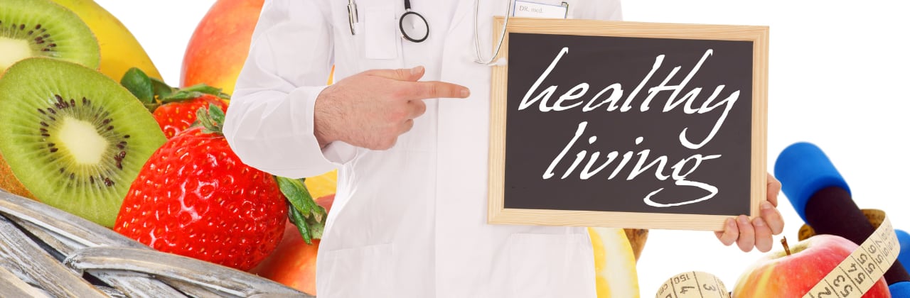 healthcare professional holding up a small chalkboard with the words healthy living written on it  surrounded by whole foods and personal exercise equipment depicting a healthier lifestyle