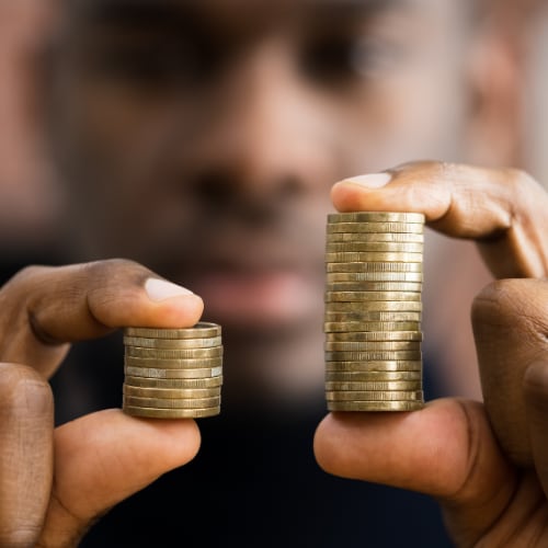 a man displaying two stacks of coins - one much larger than the other - depicting income disparity