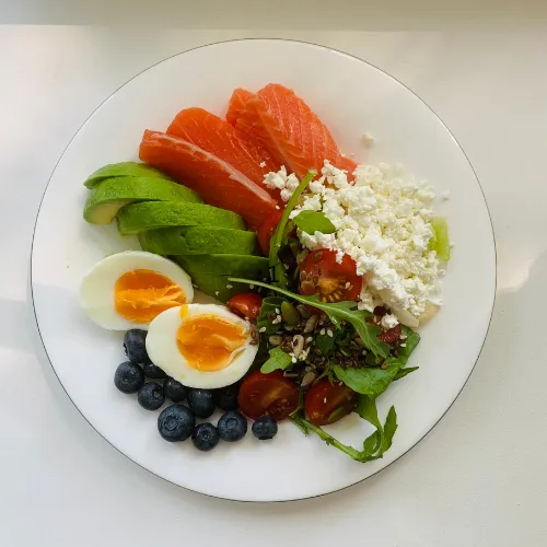A low-carbohydrate meal with eggs, avocado, and protein foods prepared in a home kitchen.