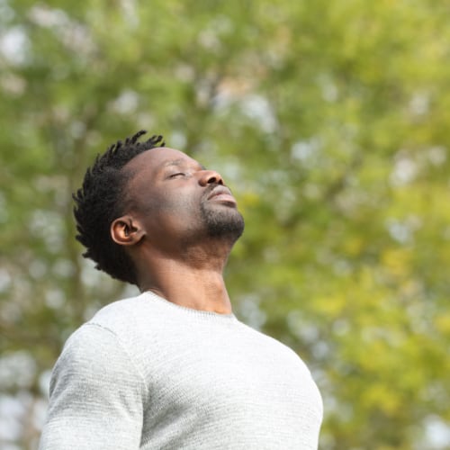 man outside in nature deep breathing