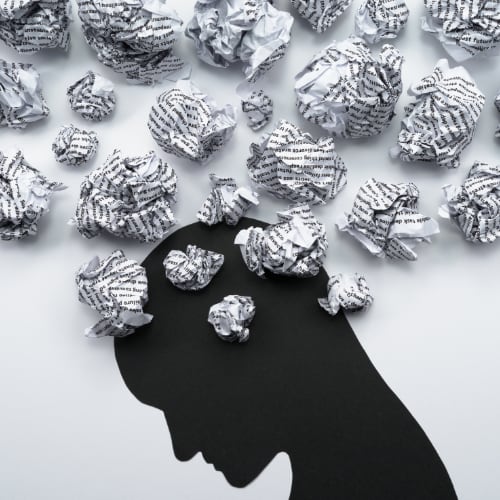 illustration of a bowed head with many crumpled pieces of paper above head depicting mental stress from data overload