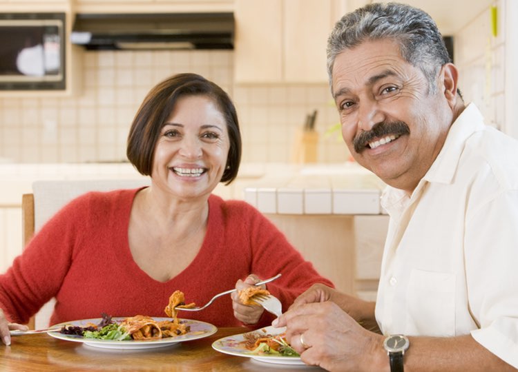 older hispanic couple enjoying home-cooked meal together