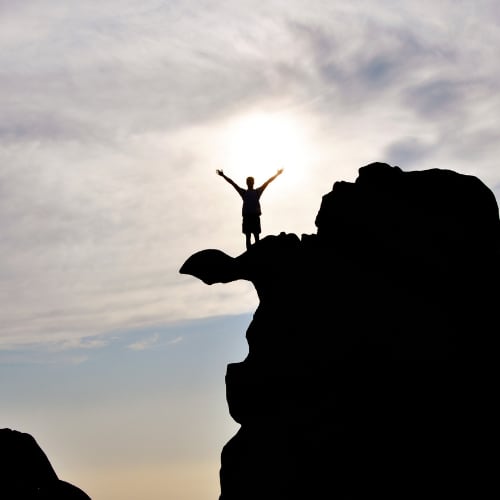 man victorious at the peak of a rocky summit