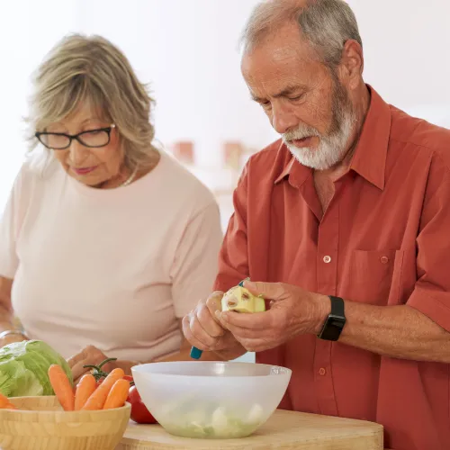 A person preparing simple meals in an organized kitchen, reflecting consistent daily routines that support digestive stability.