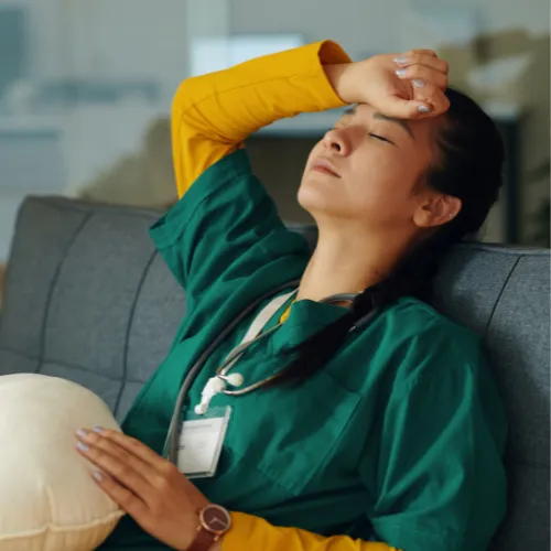A mentally and physically exhausted person sitting quietly after prolonged periods of stress and insufficient recovery.