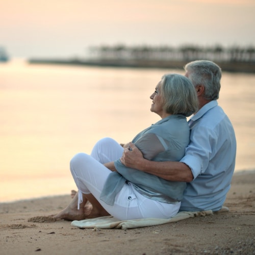 senior couple on beach gazing out at the water
