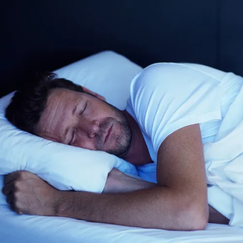 A person sleeping peacefully in a calm bedroom environment that reflects restorative recovery and rest.