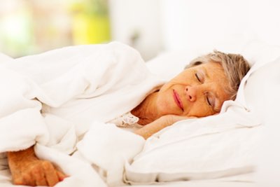 Elderly woman sleeping comfortably in bed.