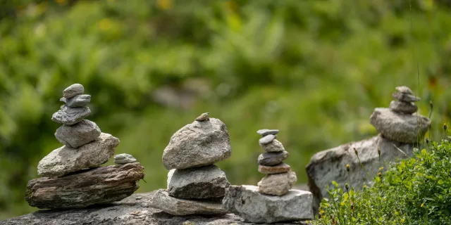 Four stacked stones balanced on a grassy hillside in natural light