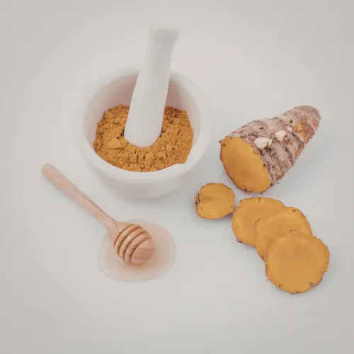 Turmeric root, turmeric powder, and turmeric supplement capsules arranged together in a kitchen setting.