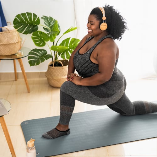 black woman exercising at home participating in. virtual class using her laptop computer