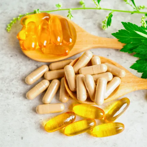Vitamin and mineral supplements in capsule and softgel form placed on wooden spoons.