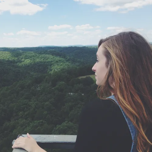 A person looking out over a scenic landscape in quiet reflection, representing perspective, meaning, and emotional resilience.