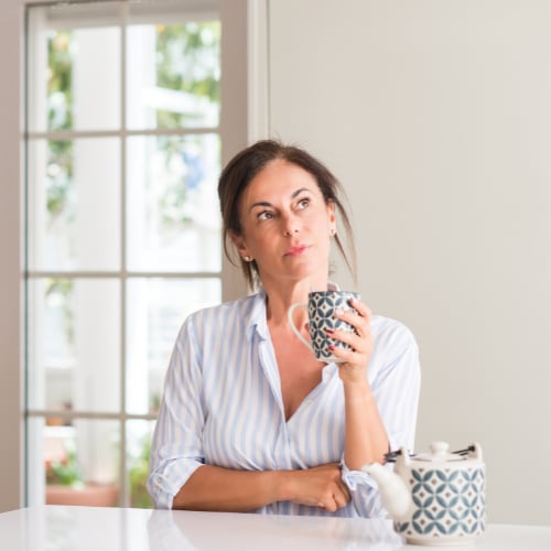 woman drinking a cup of hot tea pondering a thought