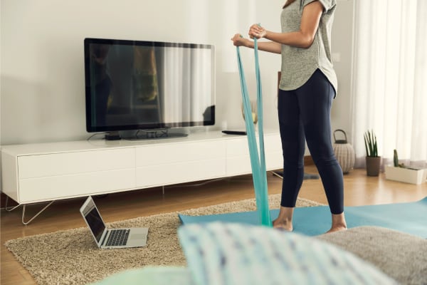 woman exercising with bands on a floor-mat at home in her living room