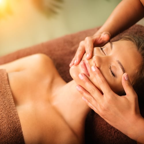a woman getting a massage, therapist working in her facial area
