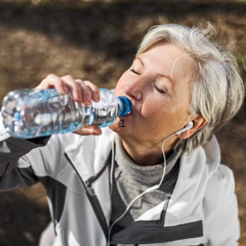 woman outdoors hydrating with water bottle