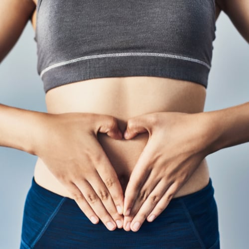 Woman Making Heart Shape With Hands on Stomach