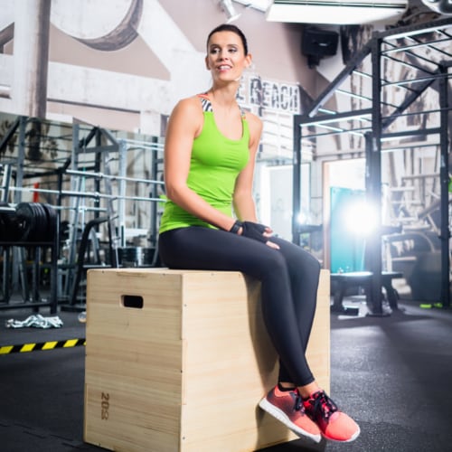 woman in a fitness gym sitting on a box used for exercises