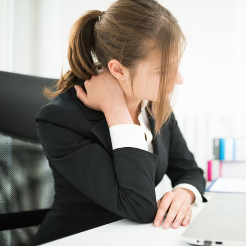 younger woman working at desk having neck pain